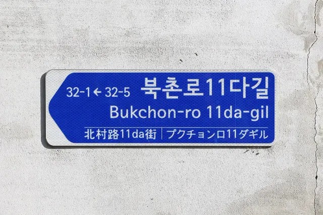 首爾北村牆面上的藍白街名牌，寫北村路11da街，並列韓文、羅馬字、中文與日文。
