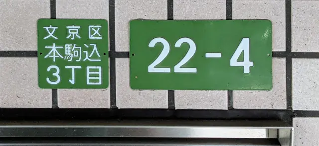 東京本駒込兩塊綠白地址牌，左牌寫文京區本駒込3丁目，右牌寫22-4。
