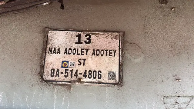 阿克拉的實拍街牌。「13」是門牌；「NAA ADOLEY ADOTEY ST」是街名，ST 為 Street 縮寫；「GA-514-4806」為數位地址，GA 是系統中的阿克拉代碼。