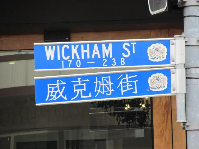 布里斯本藍底白字WICKHAM ST 170–238街牌，下方另有威克姆街漢字牌，兩牌右側皆有市徽。