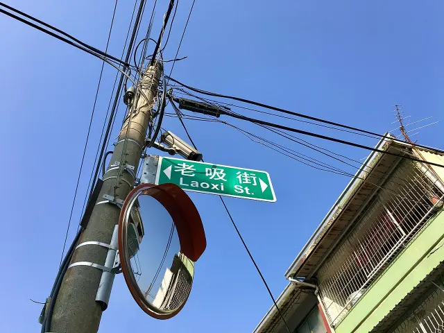 嘉義老吸街的綠底白字中英文街牌，旁邊設有路口凸面鏡。