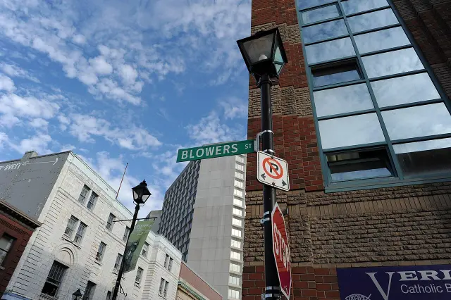 哈利法克斯街角綠底白字BLOWERS ST街牌，背景為磚牆、窗戶與路燈。