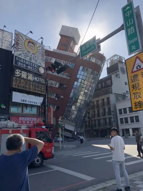 花蓮中山路與重慶路街牌，背景為2024年4月3日地震後傾斜的天王星大樓。