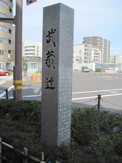 金澤武藏辻路口的灰色石柱，正面為黑色漢字，側面刻有假名及地名由來。