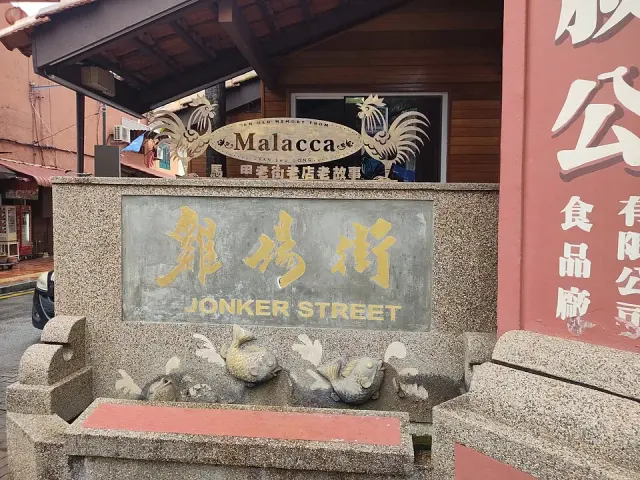 馬六甲座椅旁的灰色街名標誌，以金黃色中文雞場街與英文JONKER STREET上下排列。