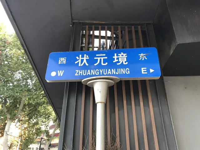 南京狀元境藍色街牌，白字拼音位於街名下方，兩端標示東西方向。
