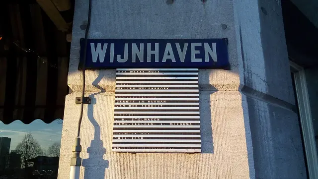 鹿特丹的實拍街牌。上牌「WIJNHAVEN」為葡萄酒港街名；下牌「HET WITTE HUIS」及1897–1898說明白屋建築，年份不是門牌號碼。