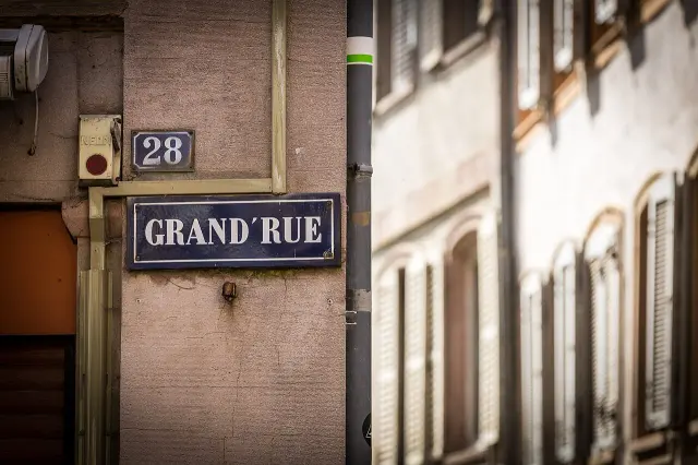 史特拉斯堡的實拍街牌。「GRAND’RUE」為大街名稱，上方獨立小牌「28」是門牌號碼；兩者合讀形成地址線索。