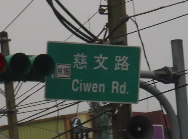 桃園慈文路綠色街牌，左側附有桃十六道路編號，旁邊為交通號誌。