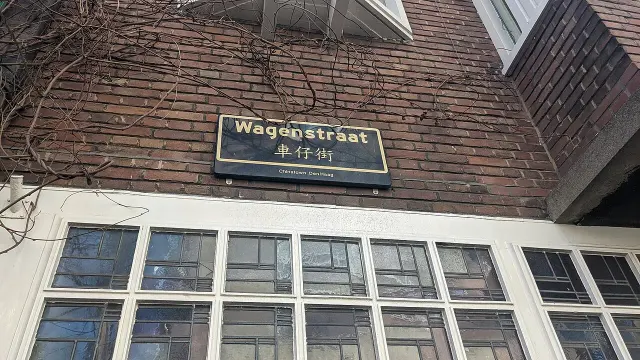 海牙的實拍街牌。上行「Wagenstraat」為荷蘭文街名，中行是中文「車仔街」，下行「Chinatown Den Haag」指海牙唐人街。