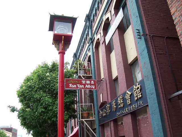 維多利亞番攤里入口紅色Fan Tan Alley牌，白色漢字右起為番攤里，旁有中式紅色路燈。