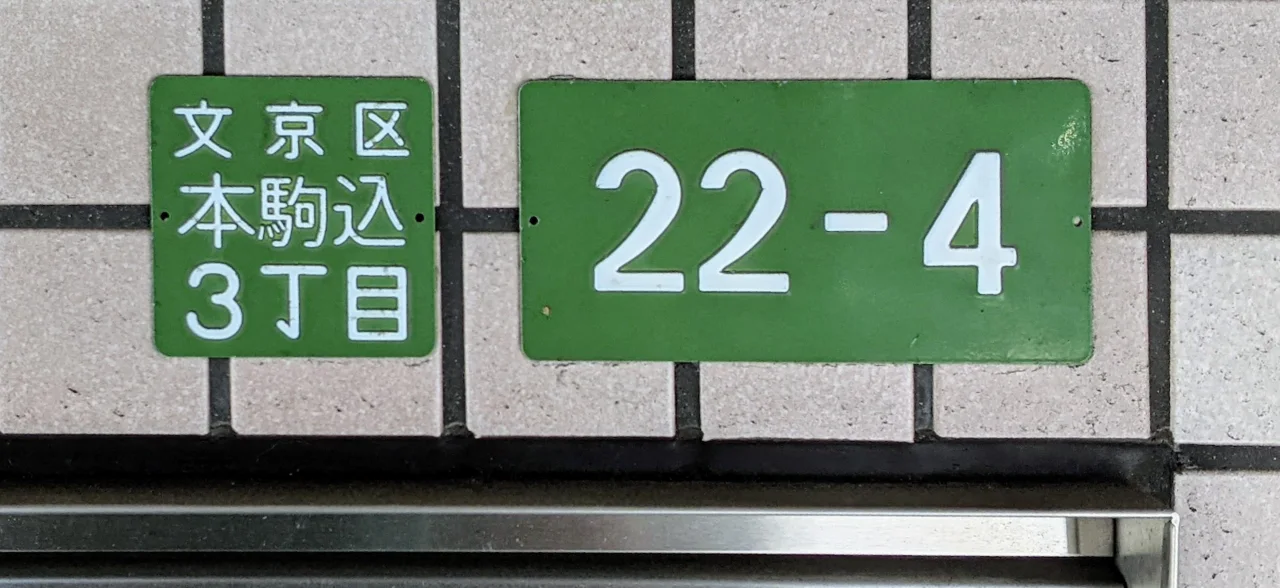 東京本駒込兩塊綠白地址牌，左牌寫文京區本駒込3丁目，右牌寫22-4。