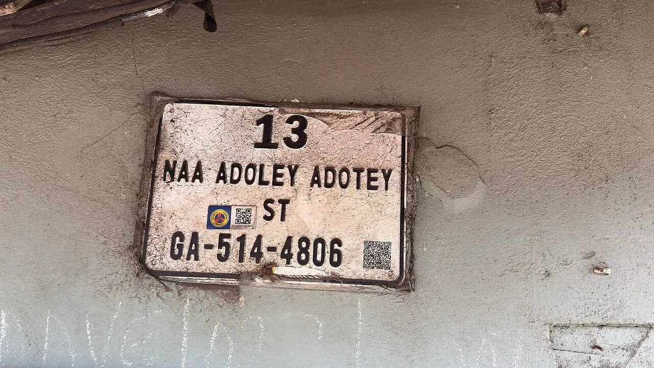 阿克拉的實拍街牌。「13」是門牌；「NAA ADOLEY ADOTEY ST」是街名，ST 為 Street 縮寫；「GA-514-4806」為數位地址，GA 是系統中的阿克拉代碼。