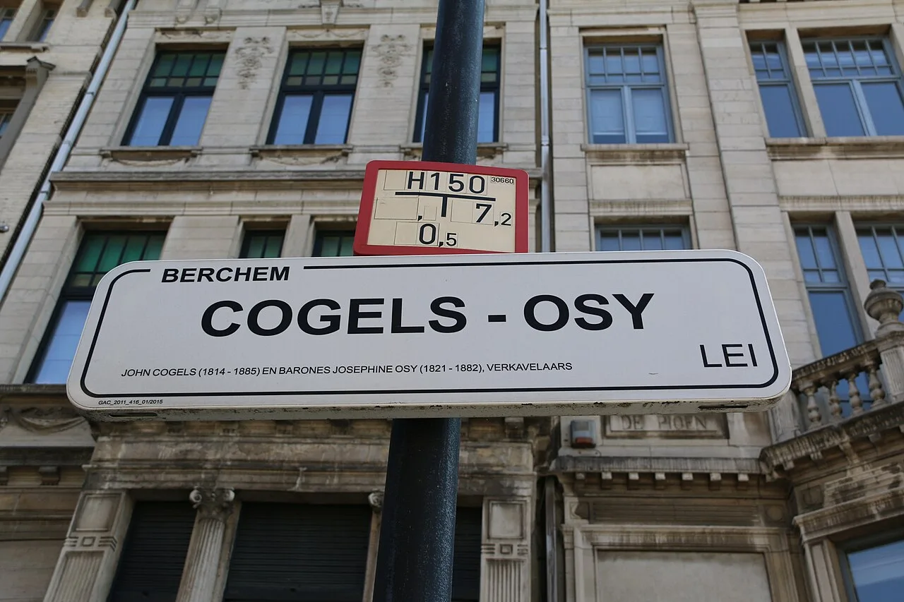 安特衛普的實拍街牌。主名「COGELS–OSY」與右下「LEI」合讀為大道名;左上BERCHEM是地區名,小字列John Cogels與Josephine Osy。