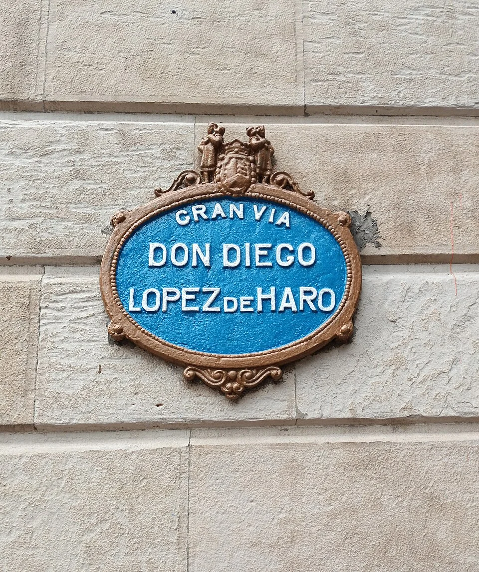 畢爾包石牆上的藍底橢圓街牌，分行寫GRAN VIA DON DIEGO LOPEZ DE HARO，頂端帶徽飾。