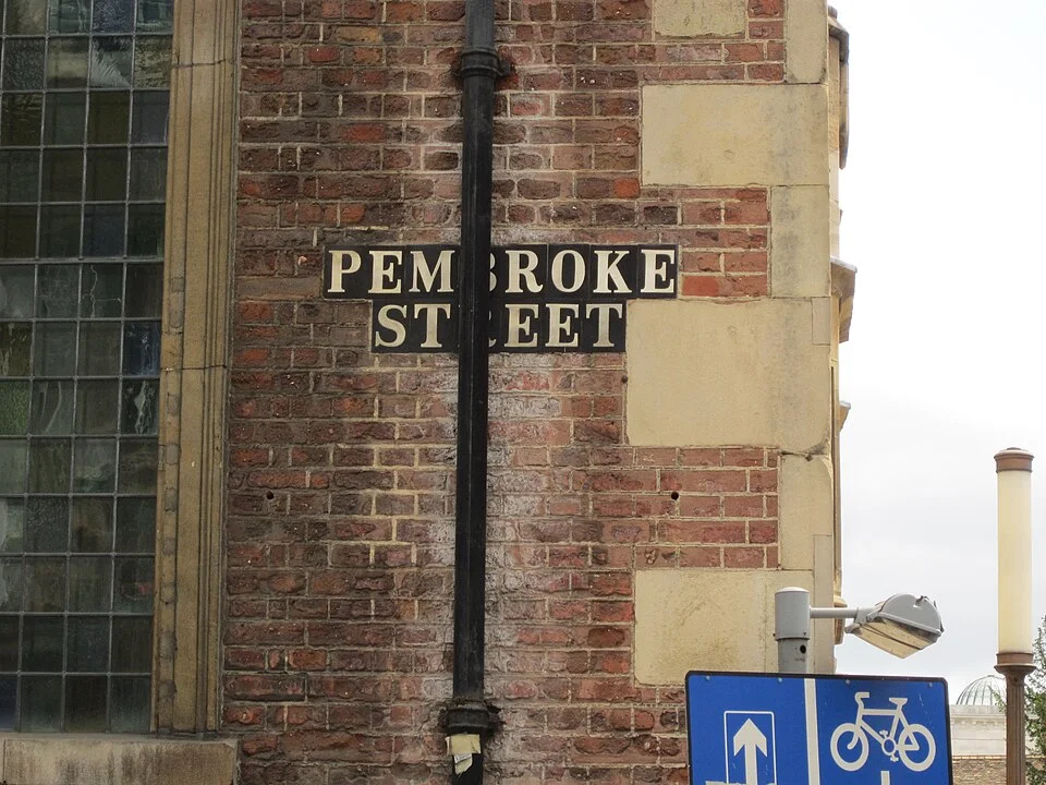 劍橋磚牆上的PEMBROKE STREET淺底黑字街牌，中央部分文字被黑色落水管遮住。