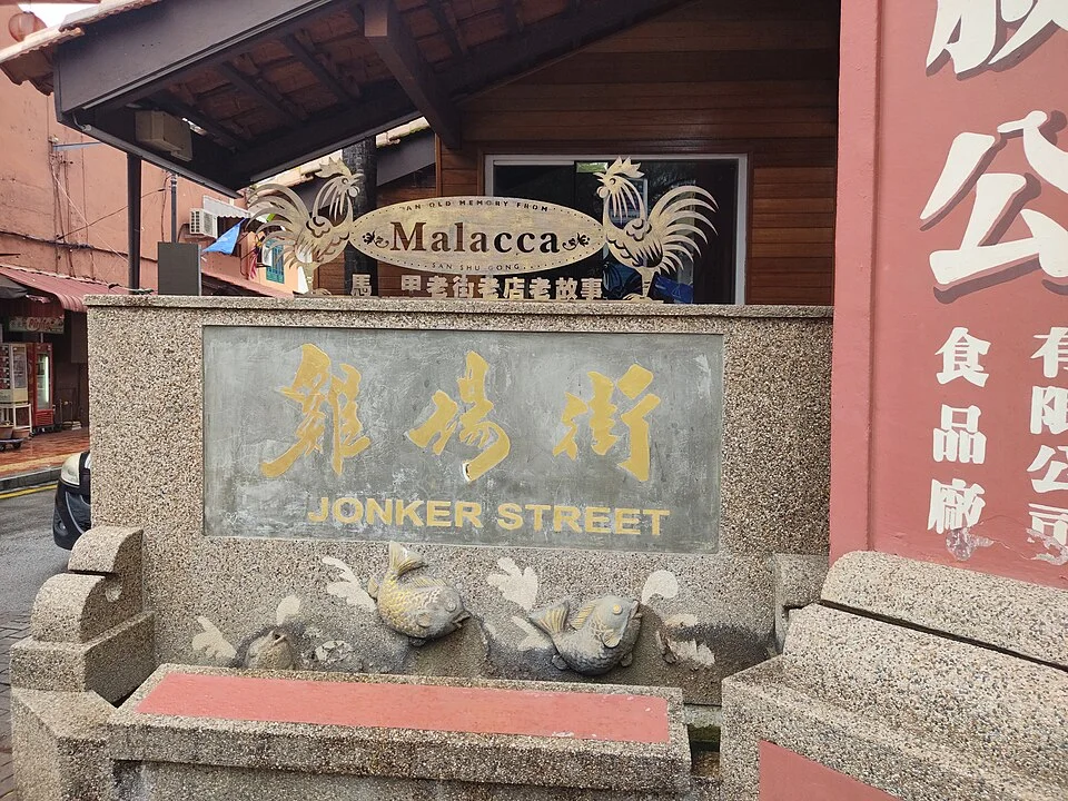 馬六甲座椅旁的灰色街名標誌,以金黃色中文雞場街與英文JONKER STREET上下排列。