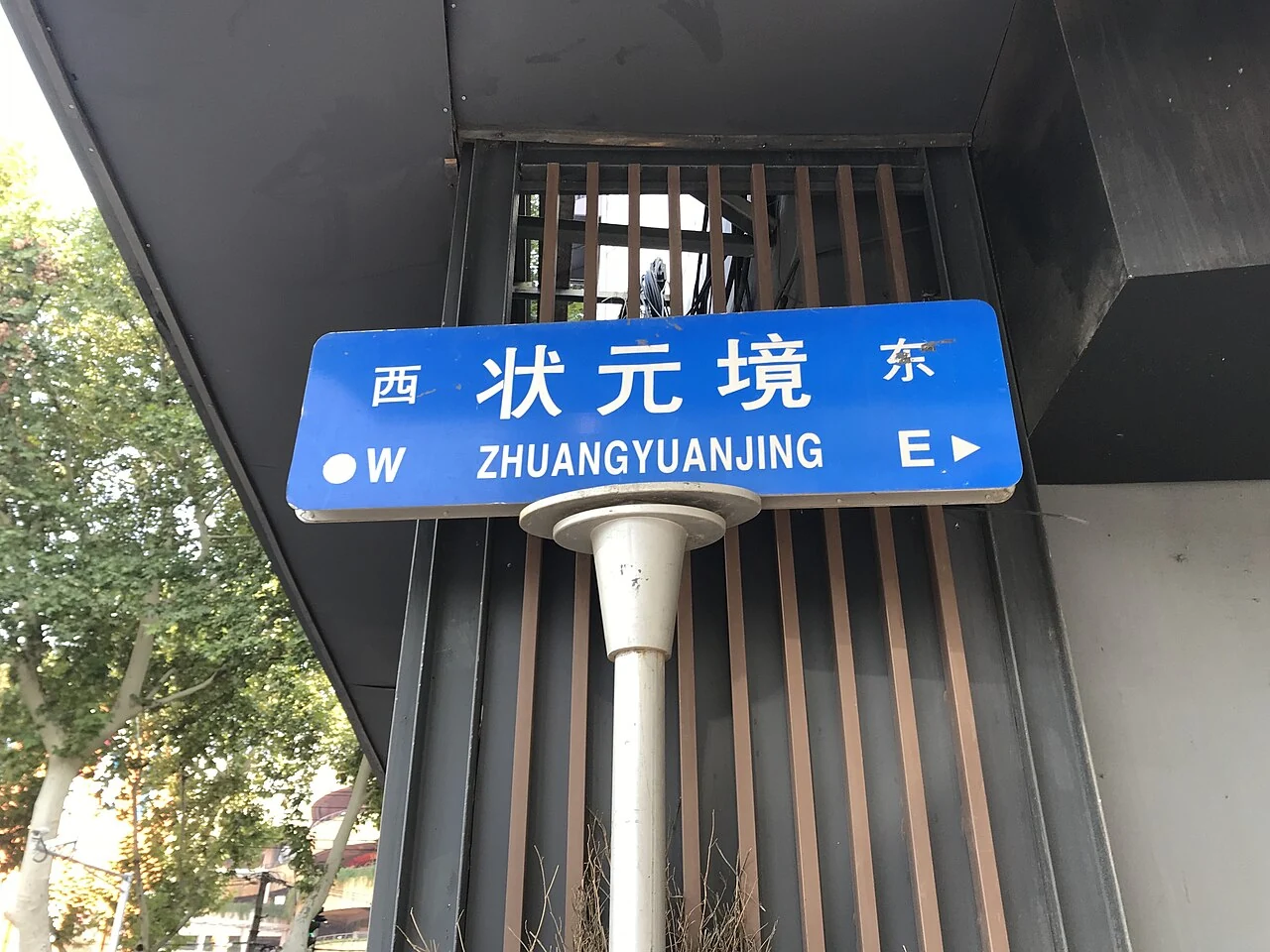 南京狀元境藍色街牌,白字拼音位於街名下方,兩端標示東西方向。