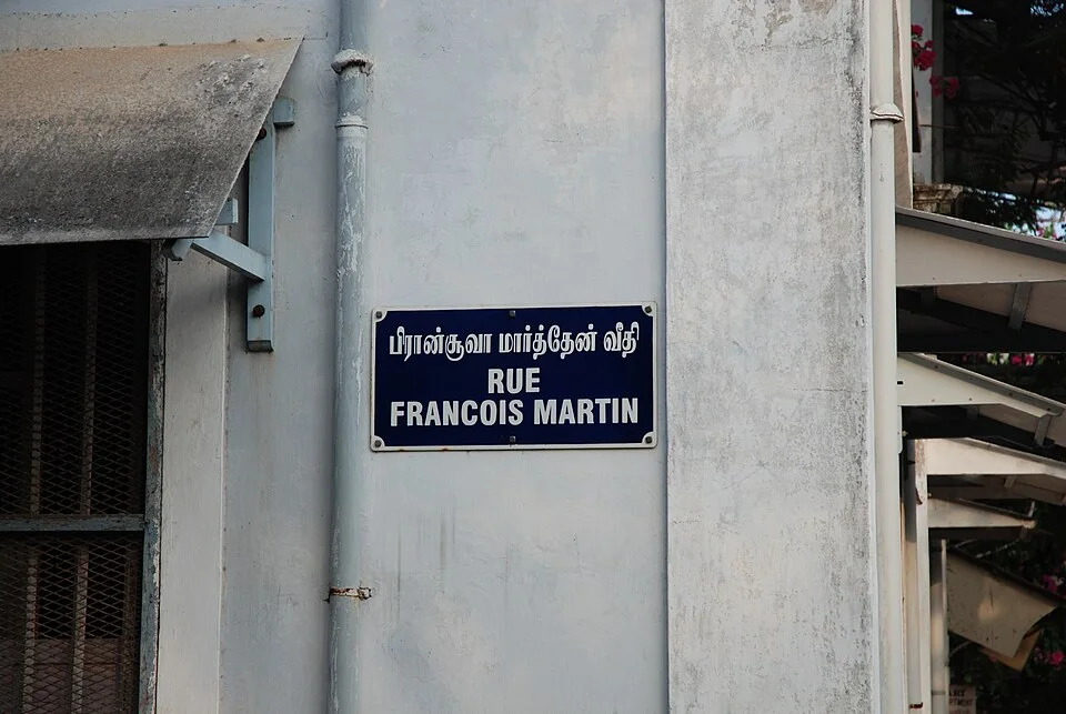 本地治里淺色牆面上的深藍雙語街牌，上為泰米爾文，下為RUE FRANCOIS MARTIN。