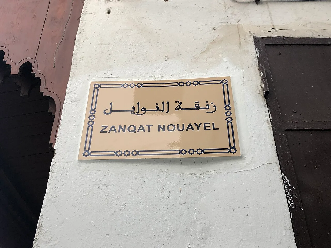 拉巴特的實拍街牌。「ZANQAT NOUAYEL」為巷名的拉丁字母轉寫,上方為阿拉伯文;Zanqat 表示巷道,畫面沒有門牌。