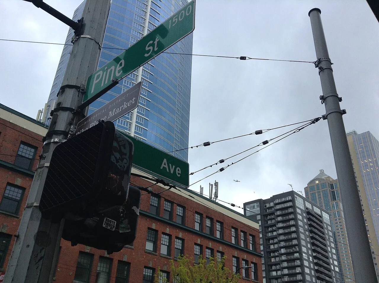 西雅圖Pine St綠色街牌，旁有部分被號誌遮住的派克市場歷史街區棕色標牌。