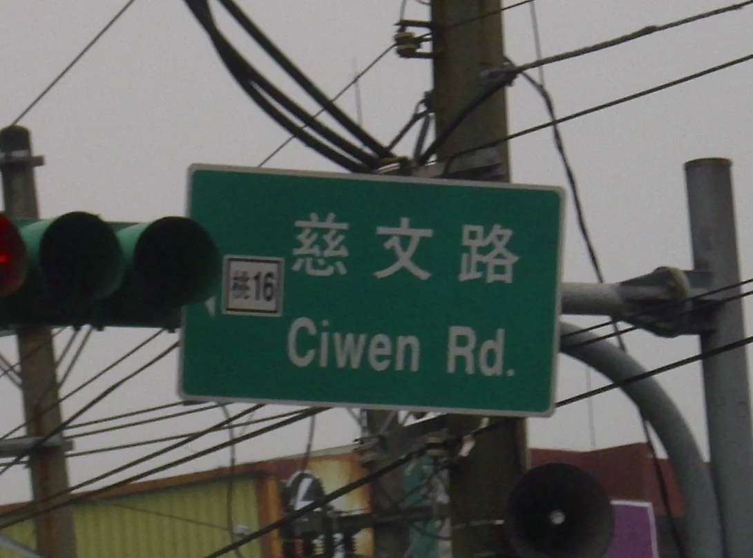 桃園慈文路綠色街牌,左側附有桃十六道路編號,旁邊為交通號誌。
