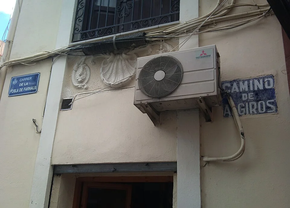 瓦倫西亞牆角兩塊街牌並置，左為藍底白字CARRER DE LA POBLA DE FARNALS，右為磨損的CAMINO DE ALGIROS。