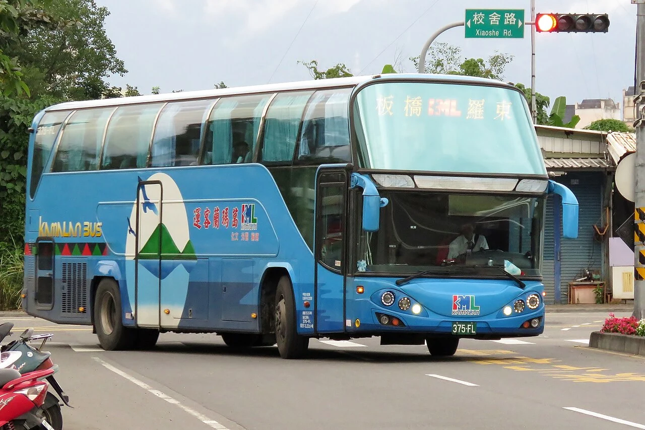 宜蘭校舍路綠色中英文街牌位於號誌上方，前景為行經路口的客運。